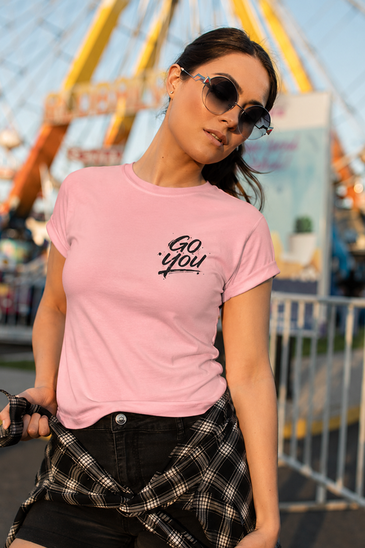 Woman wearing a pink t-shirt with 'Go You' text at an amusement park.